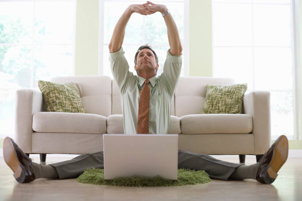 Businessman Stretching While Working on His Laptop --- Image by © Royalty-Free/Corbis (Internet/Site Exame)