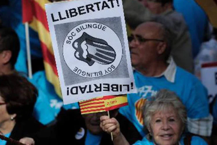 Mulher com cartaz bilíngue: estudo é o primeiro a demonstrar que os efeitos protetores do bilinguismo podem se estender para as pessoas que são analfabetas (Josep Lago/AFP)