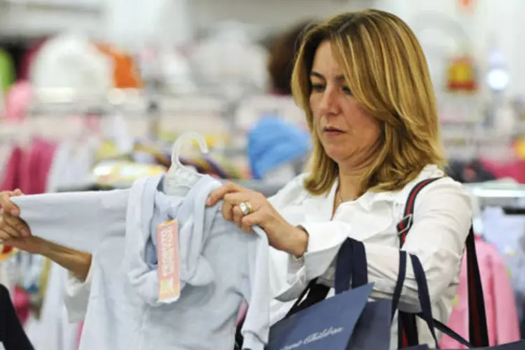 
	Mulher compra roupas em loja: proje&ccedil;&atilde;o de crescimento anual das vendas no varejo foi revisada para baixo, de 4,5% para 4%
 (Paulo Fridman/Bloomberg News)