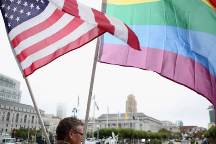 Homem segura a bandeira gay e a bandeira dos Estados Unidos (Justin Sullivan/Getty Images)