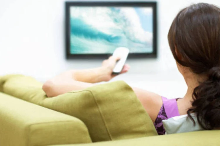 
	Mulher assiste televis&atilde;o: cliente precisar&aacute; reconfigurar suas op&ccedil;&otilde;es personalisadas de canais favoritos, bloqueios de canal e agendamentos de grava&ccedil;&atilde;o
 (.)