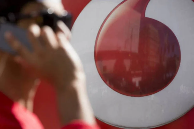 
	Homem falando ao celular passa em frente a uma loja da Vodafone: na Europa, ela j&aacute; comprou a brit&acirc;nica Cable &amp; Wireless, em 2012
 (Jason Alden/Bloomberg)