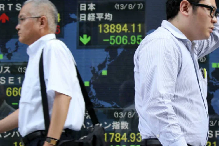 
	Pedestres passam por tel&atilde;o que mostra o &iacute;ndice Nikkei: &iacute;ndice japon&ecirc;s encerrou a sess&atilde;o com queda de 3,1 por cento
 (Tomohiro Ohsumi/Bloomberg)