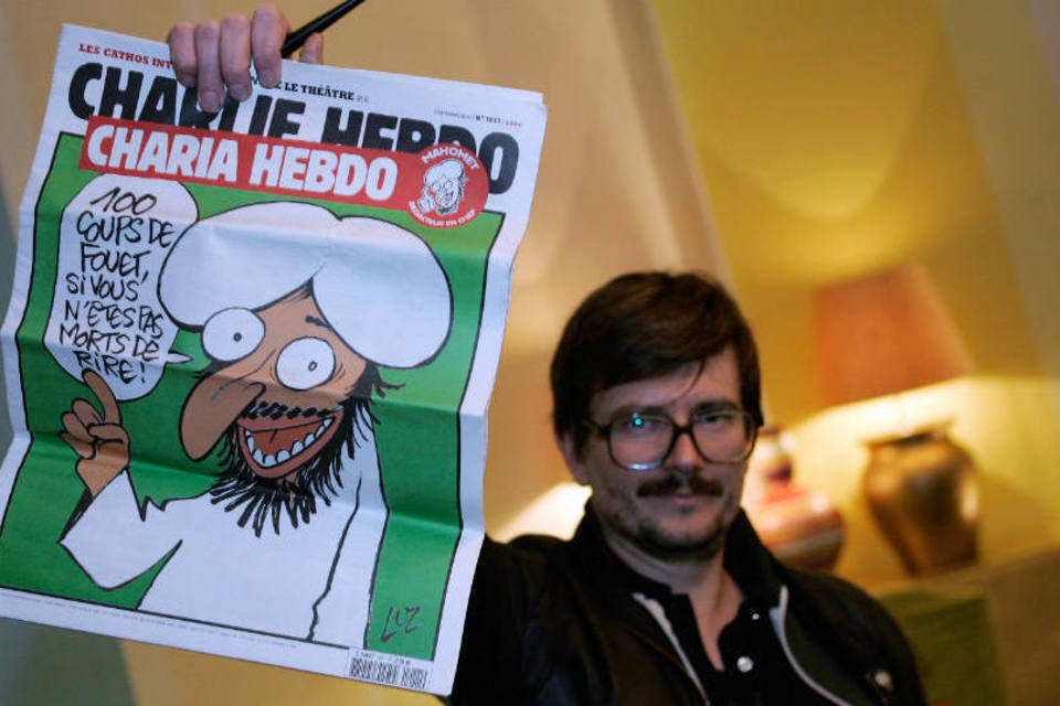 Cartunista do Charlie Hebdo segura uma capa do jornal (Getty Images)