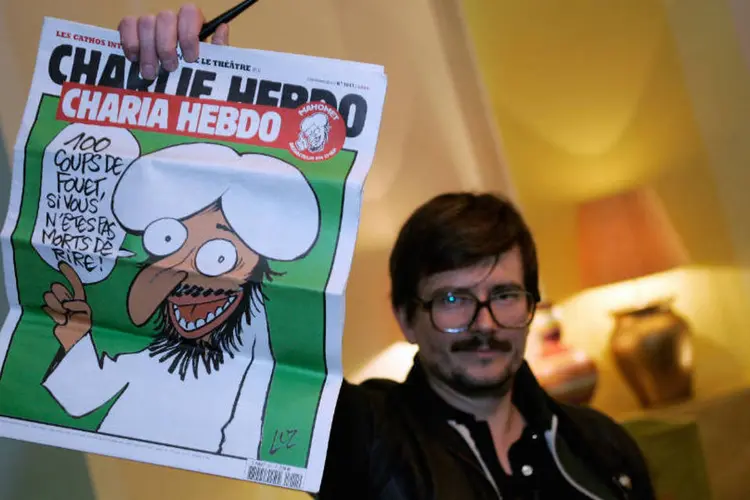 Cartunista do Charlie Hebdo segura uma capa do jornal e que diz "cem chibatadas se você não estiver morto de rir".  (Getty Images)
