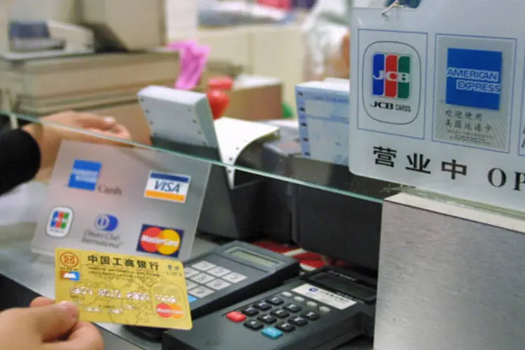 Consumido usa um cartão de crédito com a bandeira da companhia japonesa JBS em uma loja de Pequim, China (Cheng Gong/Imaginechina via Bloomberg News)