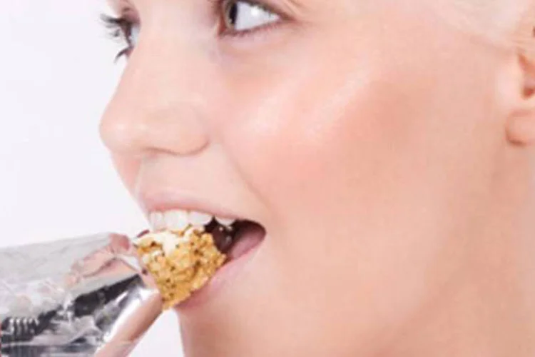 Pessoa comendo barrinha de cereais: longe de serem “light”, muitos desses produtos trazem altas concentrações de açúcar, sódio ou gordura (Runners)