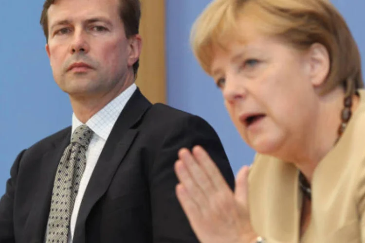 
	Steffen Seibert e Angela Merkel: mais cedo, a chanceler alem&atilde; voltou a criticar programas de est&iacute;mulo econ&ocirc;mico financiados pelo aumento da d&iacute;vida p&uacute;blica
 (Sean Gallup/Getty Images)