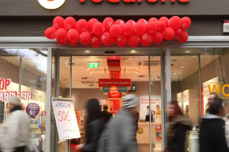 
	Consumidores passam por loja da Vodafone em Berlim: companhia est&aacute; sob press&atilde;o para mostrar que pode competir com grupos de TV a cabo com uma oferta combinada
 (Adam Berry/Getty Images)