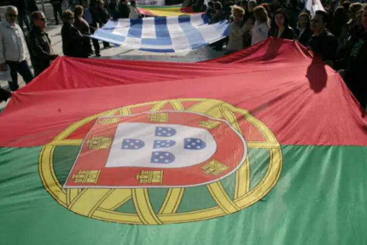 
	Manifestantes carregam bandeira de Portugal: &quot;ser&aacute; uma miss&atilde;o para colaborar com o crescimento da economia de Portugal&quot;, disse&nbsp;vice-presidente da Comiss&atilde;o Europeia
 (Milos Bicanski/Getty Images)