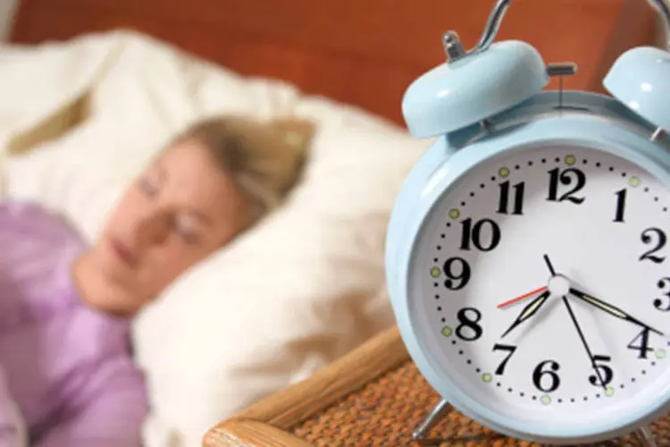 Mulher dormindo com despertador: tente transformar seu descanso em uma rotina saudável, dedicando tempo necessário para cada tarefa (Getty Images)