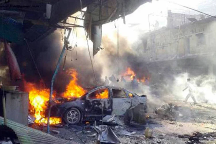 Veículos pegam fogo depois de uma explosão na cidade de Darkush, na província de Idlib, Síria
 (AFP)