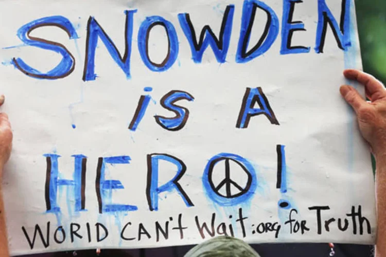 
	Ativista protesta em frente ao pr&eacute;dio da NSA com placa que diz que Edward Snowden &eacute; her&oacute;i: Assange tamb&eacute;m chamou Snowden de her&oacute;i e disse que teve contato com o ex-funcion&aacute;rio da CIA (Mario Tama/Getty Images)