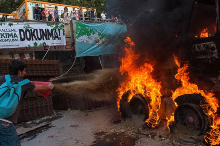 
	Manifestante tenta apagar chamas em ve&iacute;culo com balde de &aacute;gua: o&nbsp;prefeito garantiu que atualmente mil funcion&aacute;rios p&uacute;blicos do munic&iacute;pio trabalham de forma intensa para renovar e embelezar o parque Gezi.
 (Lam Yik Fei/Getty Images)