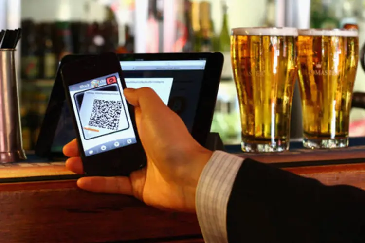 Homem paga cerveja com um celular, usando a moeda virtual Bitcoin, em um bar de Sydney, na Austrália (Cameron Spencer/Getty Images)