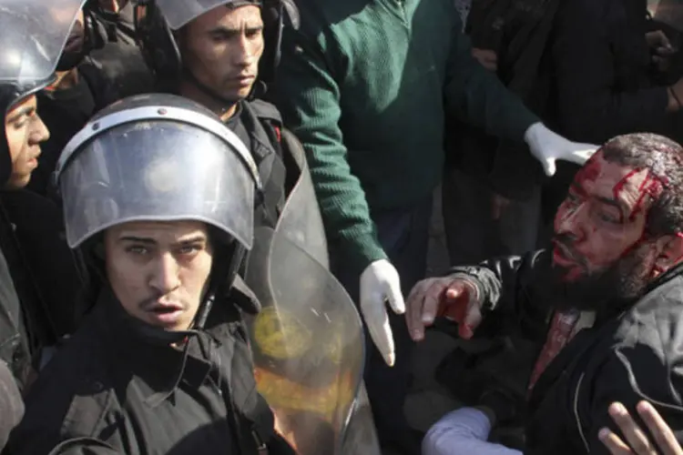 
	Um manifestante anti-Mursi (de verde) e a pol&iacute;cia paralisam um apoiador Mursi (d): a viol&ecirc;ncia explodiu depois que alguns simpatizantes repreenderam opositores
 (Stringer/Reuters)