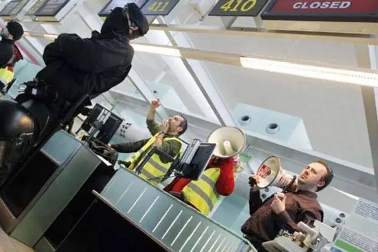 Delegados sindicais conversam com a multidão enquanto policiais montam guarda em frente ao balcão de check-in da Iberia no aeroporto de Barcelona (Albert Gea/Reuters)