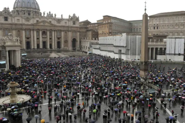 Fieis aguardam com seus guarda-chuvas na Praça de São Pedro, no Vaticano  (Alessandro Bianchi/Reuters)