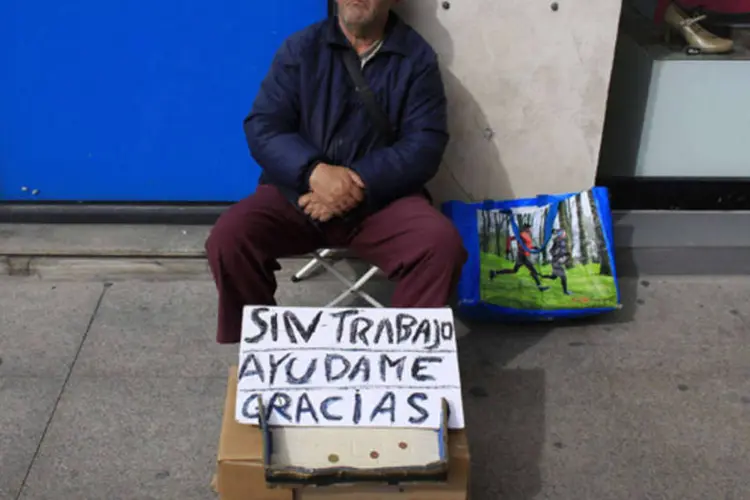 Desempregado Juan Bayes, 60 anos, dorme enquanto pede ajuda com cartaz em Andaluzia, capital de Sevilha, na Espanha (Marcelo del Pozo/Reuters)