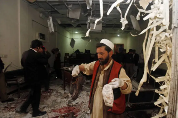 Oficial de segurança coleta evidencia no local da explosão de um homem-bomba no complexo judiciário de Peshawar (Fayaz Aziz/Reuters)