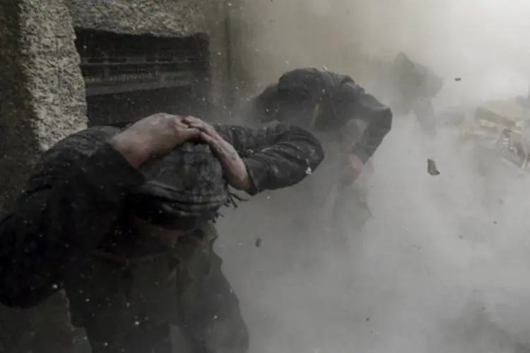 Combatente do Exército Sírio Livre corre para se proteger de disparo de tanque: acredita-se que o governo possua um arsenal de armas químicas (Goran Tomasevic/Reuters)