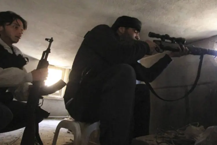 Membro do exército livre da Síria aponta sua arma através de um buraco no distrido de Saif al-Dawla, em Alepo (Giath Taha/Reuters)