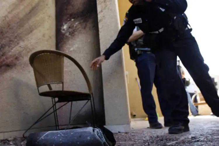 Policial israelense ao lado dos restos do foguete lançado por militantes palestinos na Faixa de Gaza (Amir Cohen/Reuters)