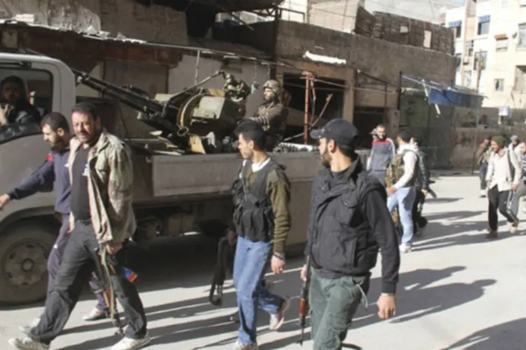 Combatentes armados do Exército Sírio Livre andam na rua em Sayed Makdad, em Damasco, em foto da emissora Shaam News (Ward Al-Keswani/Shaam News Network/Divulgação)