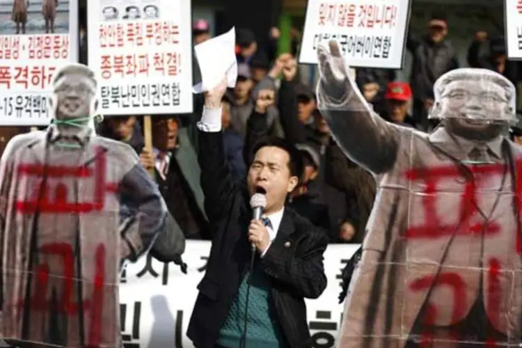 Manifestantes anti-Coreia do Norte entre as imagens de Kim Il-sung e Kim Jong-il durante um protesto que marca o 3º aniversário do naufrágio do navio sul-coreano Cheonan (Kim Hong-Ji/Reuters)