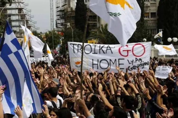 Estudantes seguram bandeiras grega e cipriota e gritam palavras de ordem em uma manifestação contra a troika do lado de fora do palácio presidencial, em Nicósia (Yannis Behrakis/Reuters)