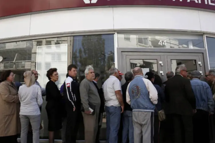 
	Clientes fazem fila na frente de uma ag&ecirc;ncia do banco Laiki a espera de sua reabertura em Nicosia, no final de mar&ccedil;o
 (Yorgos Karahalis/Reuters)