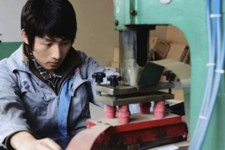 Trabalhador manipula máquina em uma fábrica em Qingdao, província de Shandong, na China (China Daily/Reuters)