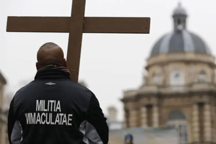 Homem segura uma cruz em manifestação contra o casamento gay no lado do prédio do senado francês, em Paris (Christian Hartmann/Reuters)