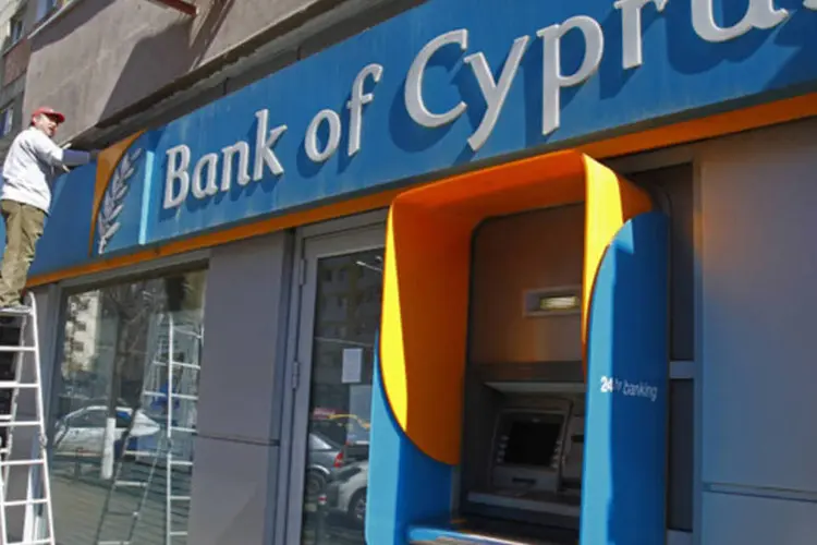 Funcionário pinta a parede acima de uma agência do Bank of Cyprus, em Bucareste, na Romênia (Bogdan Cristel/Reuters)