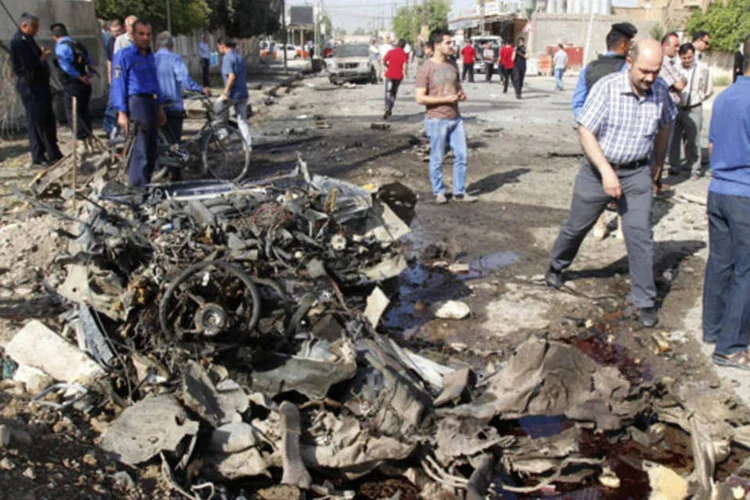 Membros da força de segurança do Iraque junto aos destroços de um carro-bomba, em Kirkuk, ao norte de Bagdá (Ako Rasheed/Reuters)