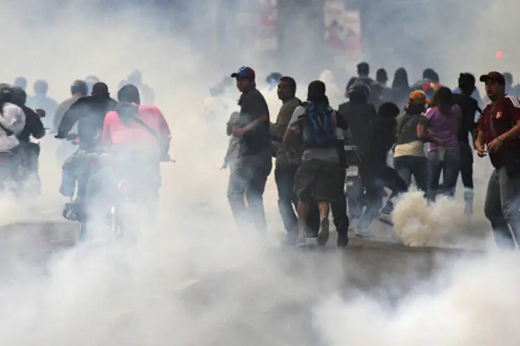Partidários da oposição correm de gás lacrimogênio lançado pela polícia enquanto pediam a recontagem dos votos da eleição (Christian Veron/Reuters)