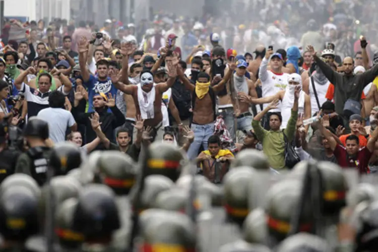 
	Apoiadores do l&iacute;der da oposi&ccedil;&atilde;o Henrique Capriles enfrentam policiais em Caracas: eles pedem a recontagem dos votos
 (Christian Veron/Reuters)