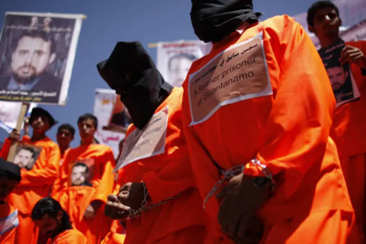 
	Ex-detentos de Guant&aacute;namo vestem capuzes pretos durante protesto: Uruguai ir&aacute; abrigar seis detentos
 (Khaled Abdullah/Reuters)