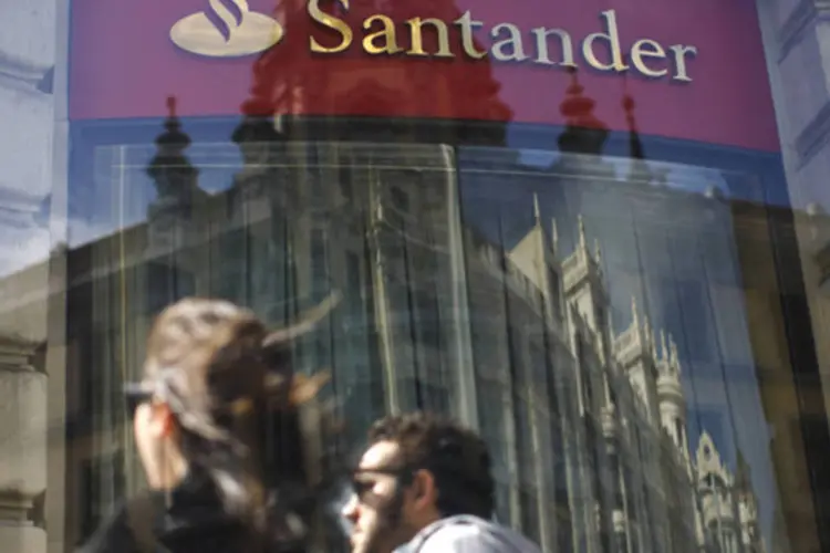 
	Pessoas passam em frente a uma ag&ecirc;ncia do banco Santander, em Madri
 (Paul Hanna/Reuters)