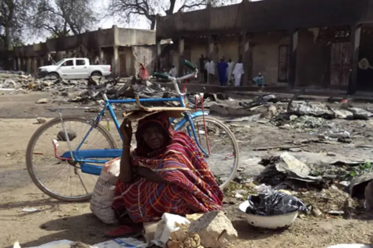 Mulher senta-se em meio às ruínas do Mercado Bama incendiado, que foi destruído por atiradores em um ataque em Maiduguri, nordeste da Nigéria (Afolabi Sotunde/Reuters)