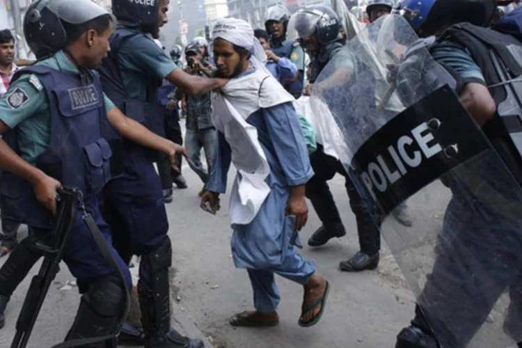 Polícia tenta deter ativista do Hefajat-e-Islam durante confrontos diante da mesquita nacional, em Daca (Andrew Biraj/Reuters)
