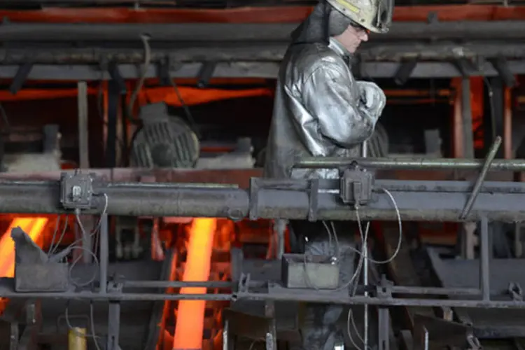 Trabalhador entre vigas de aço incandescente na fábrica da empresa alemã Arcelor Mittal, em Hamburgo, Alemanha (Fabian Bimmer/Reuters)