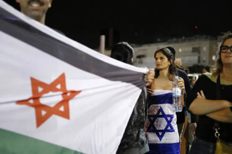 
	Homem segura uma bandeira de Israel com as cores da Palestina: atual negocia&ccedil;&atilde;o de paz, iniciada em julho, parou por causa da insist&ecirc;ncia de Israel em ser reconhecido como um Estado judeu e ampliar seus assentamentos
 (Amir Cohen/Reuters)