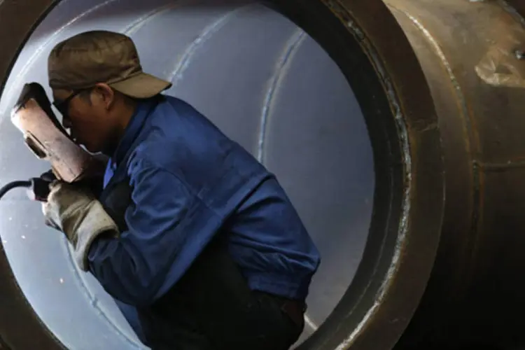 Trabalhador solda uma turbina de água em uma fábrica em Jinhua, na província de Zhejiang, na China (William Hong/Reuters)