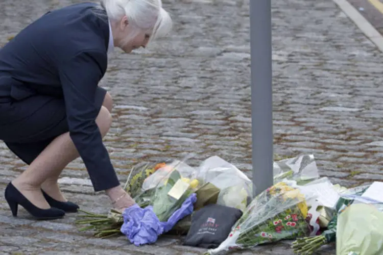 Mulher coloca flores do lado de fora de edifício militar, perto do local onde um soldado britânico foi assassinado em Woolwich, em Londres (Neil Hall/Reuters)