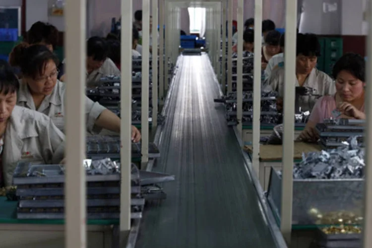 
	Funcion&aacute;rios trabalhando em uma f&aacute;brica em Jinhua, prov&iacute;ncia de Zhejiang, na China: pesquisa mostrou que a atividade industrial encolheu pela primeira vez em sete meses
 (William Hong/Reuters)