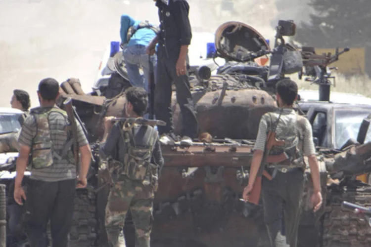 
	Membros do ex&eacute;rcito livre da S&iacute;ria no topo de um tanque de guerra pertencente &agrave;s for&ccedil;as leiais do presidente Bashar al-Assad, ap&oacute;s capturar o acampamento militar de al-Shabiba
 (Redwan Al-Homsi/Shaam News Network/Divulgação via Reuters)