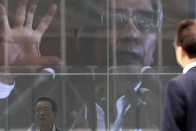 Homem olha para um painel eletrônico mostrando a imagem do presidente do Banco do Japão (BOJ), Haruhiko Kuroda, em Tóquio (Toru Hanai/Reuters)