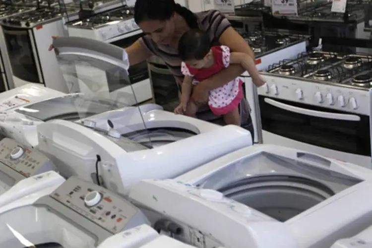 
	Mulher com crian&ccedil;a examina m&aacute;quina de lavar em loja das Casas Bahia, em S&atilde;o Paulo
 (Nacho Doce/Reuters)