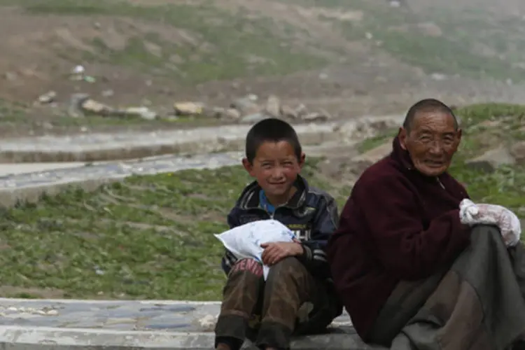 Menino e um homem tibetanos sentados em um rua próximo do monastério Dzamthang Jonang, onde Kalkyi se auto-imolou em protesto contra as leis chinesas, em Barma (Kim Kyung-Hoon/Reuters)